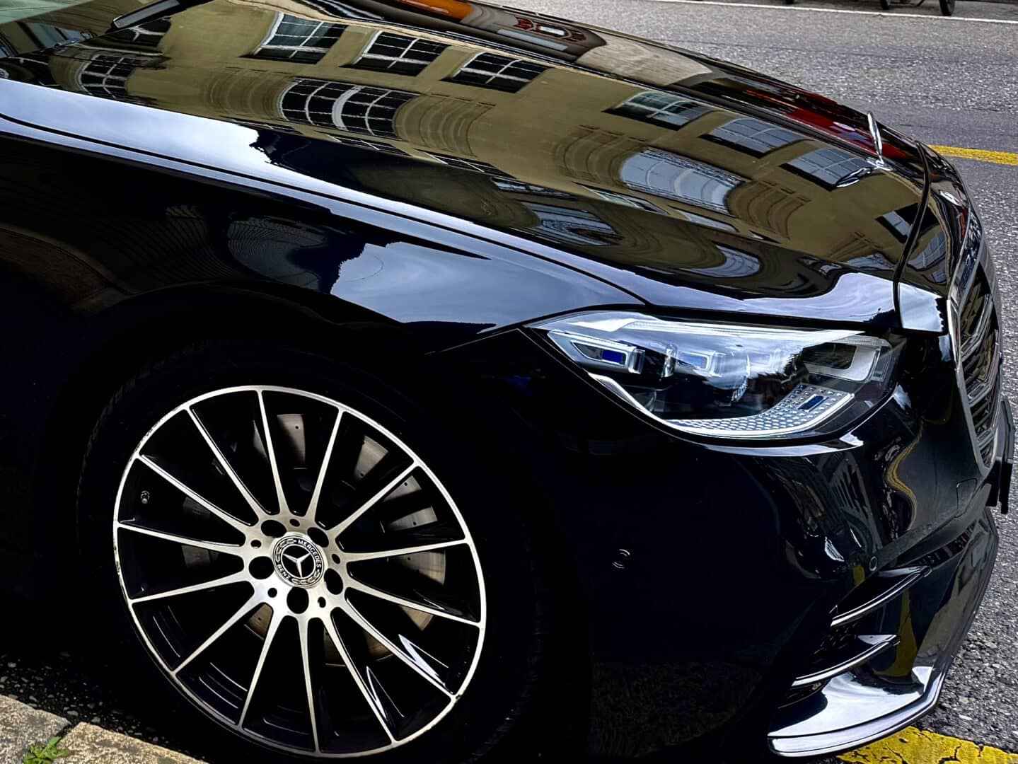 Luxury black Mercedes-Benz vehicle parked on the street, showcasing its sleek design and stylish alloy wheel. Perfect for professional transportation and chauffeur services.