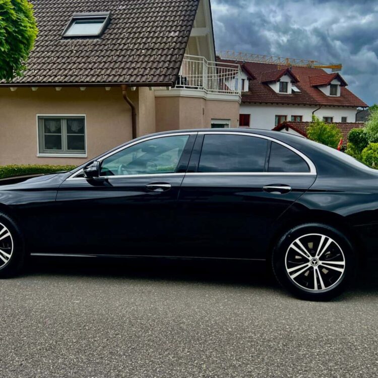 Luxury black sedan parked on residential street in Switzerland, showcasing elegant design and premium features, ideal for transportation services by Globetransporte GmbH.