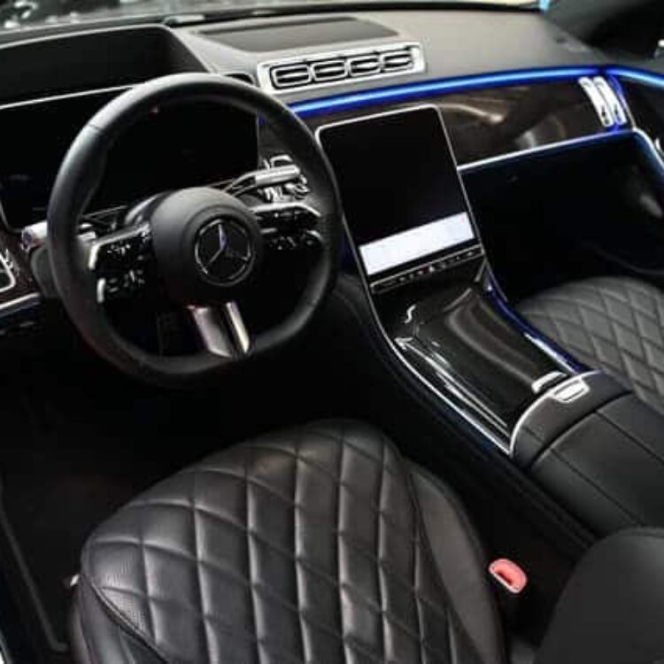 S Cass Luxury car interior featuring Mercedes-Benz dashboard, digital displays, and premium black quilted leather seats with ambient blue lighting.
