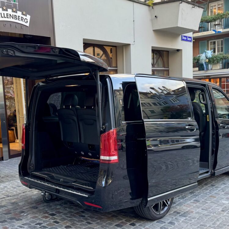 سيارة مرسيدس V-Class Black Car Service متوقفة أمام فندق Wellenberg في زيورخ، الأبواب و شنطة الحقائب استعدادًا لنقل الركاب براحة وفخامة إلى إنترلاكن